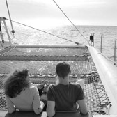 Two people sitting on a boat looking out at the ocean.