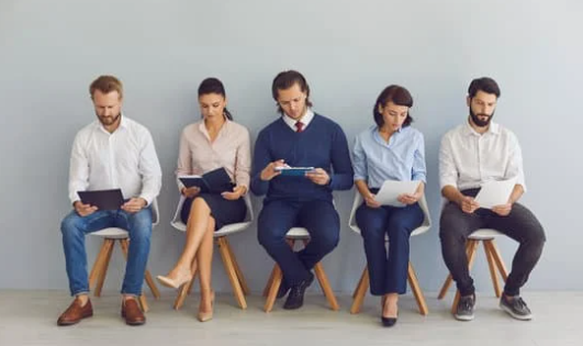 A group of people sitting in chairs looking at their phones.