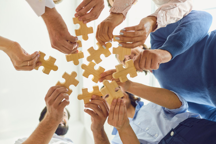 A group of people holding puzzle pieces in the air.