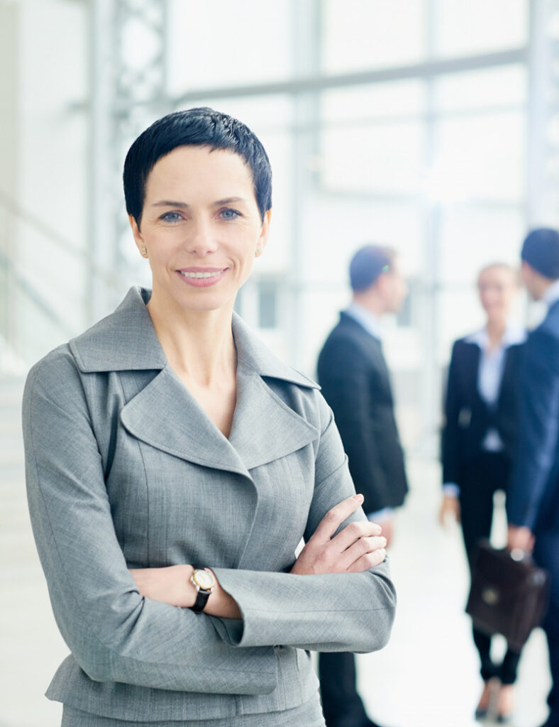 A woman in grey jacket standing next to other people.